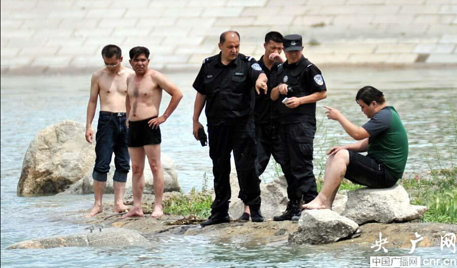 民警在河中央的小岛上询问被救男子。